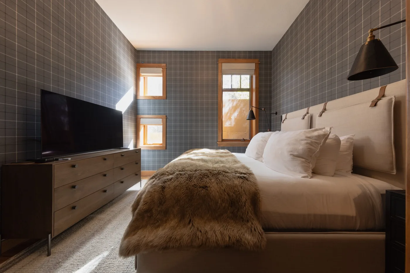 A bedroom with a bed, bedside lamps, and a television on a dresser.