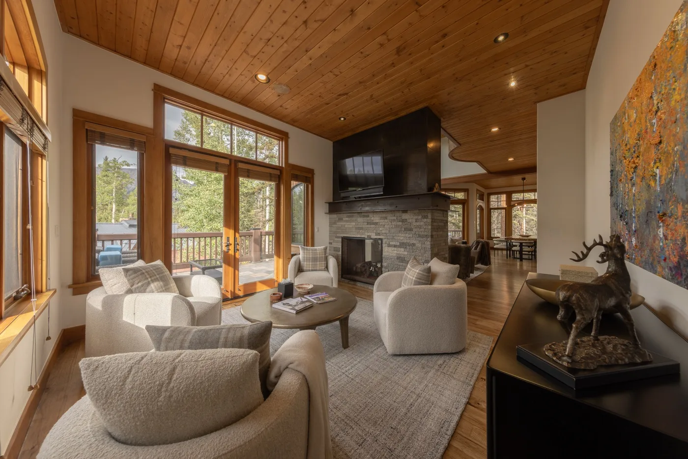 A living room with seating around a fireplace beneath a wooden ceiling.