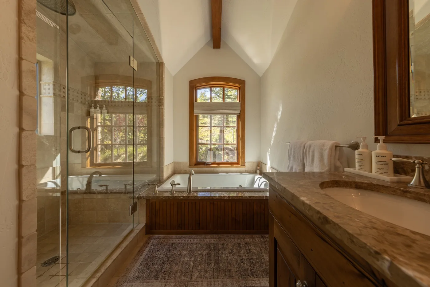 A bright bathroom with a glass shower and a window above the bathtub.