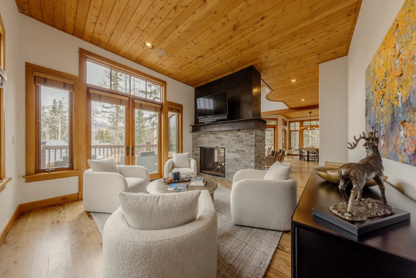 A spacious living room with seating around a stone fireplace and large windows.