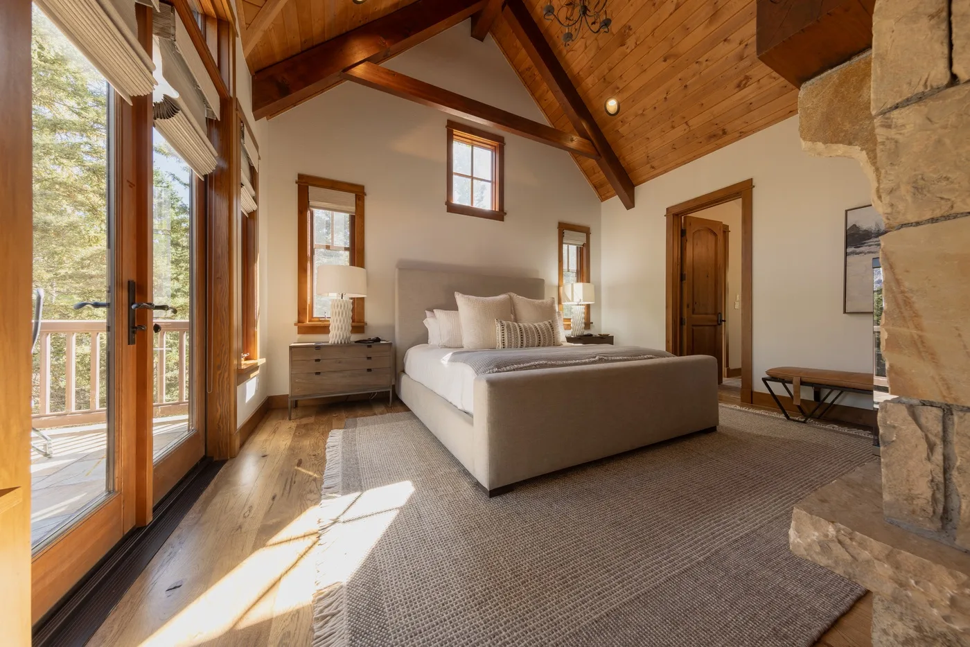 A bedroom with a bed beneath a high, wood-paneled ceiling.
