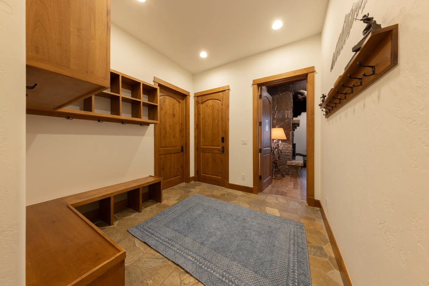 A hallway with wooden storage, a bench, and a blue rug.