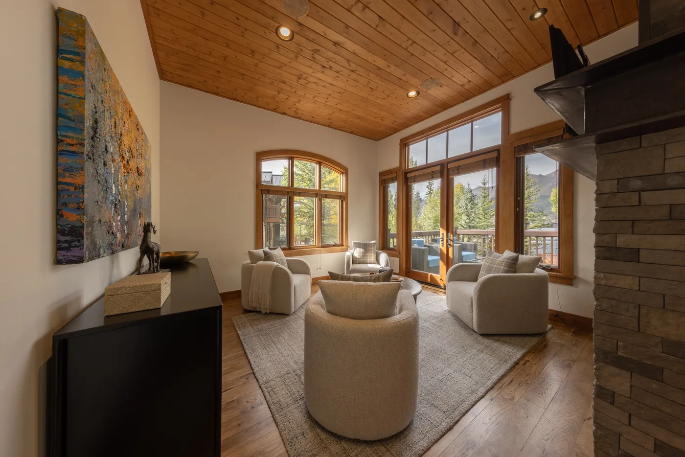 A bright living room with seating arranged around a low table beside large windows.