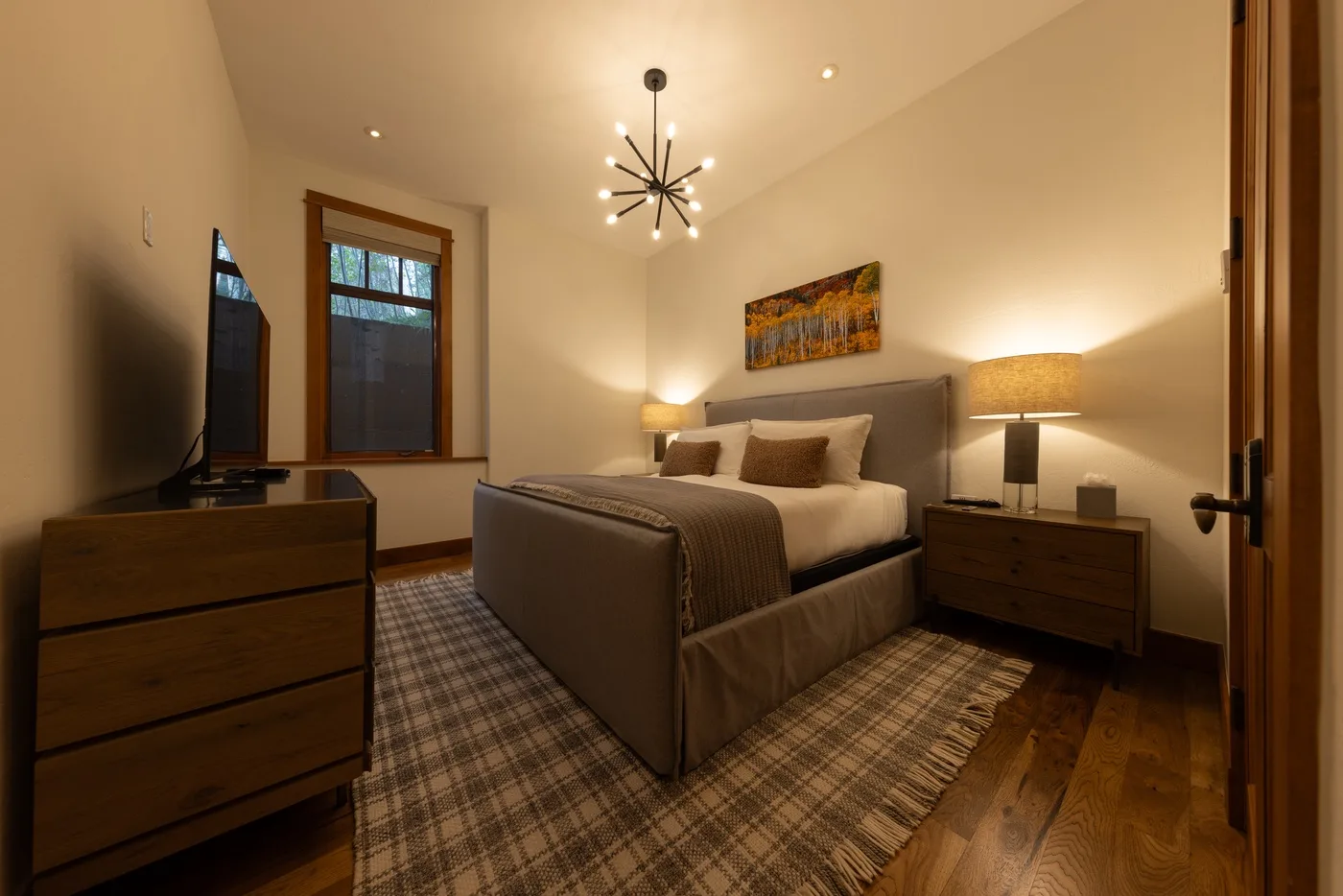 A bedroom with a bed, bedside tables, and a patterned rug.