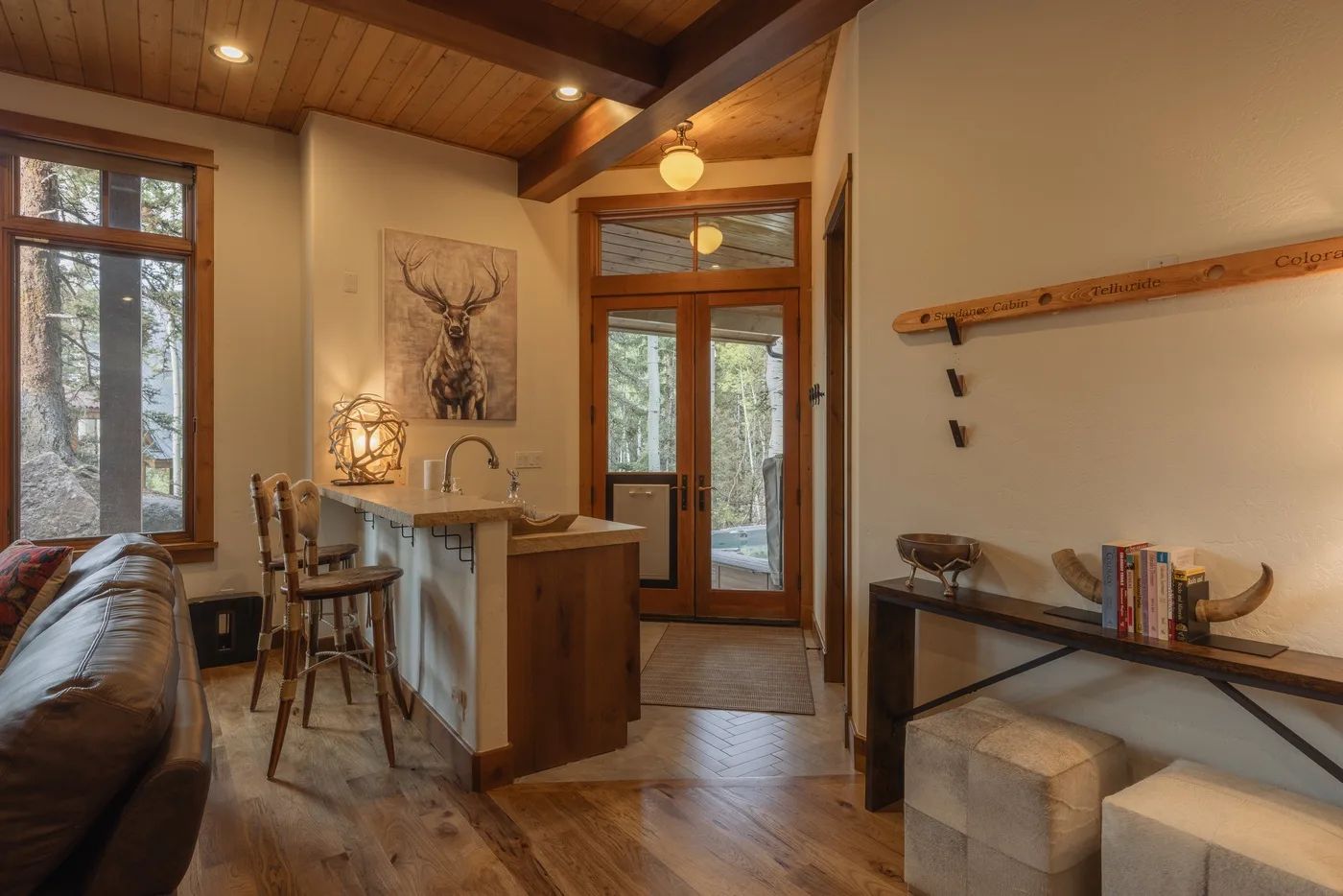 A compact interior combines a small kitchen counter, seating, and a glass door to the outdoors.