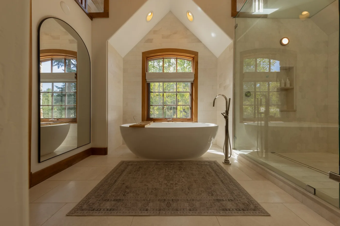 A bathroom with a freestanding tub beneath a window and a glass shower.