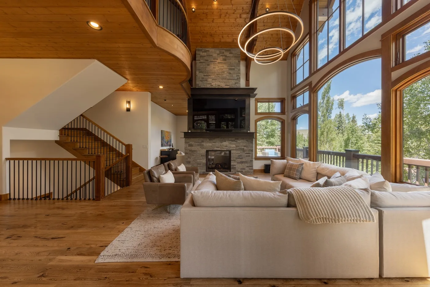A spacious living room with seating arranged around a fireplace and large windows.