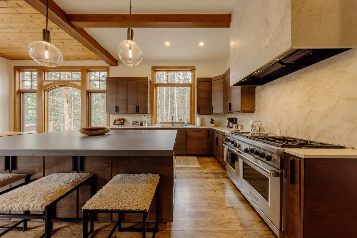 A spacious kitchen with a large island, wood cabinetry, and a range.