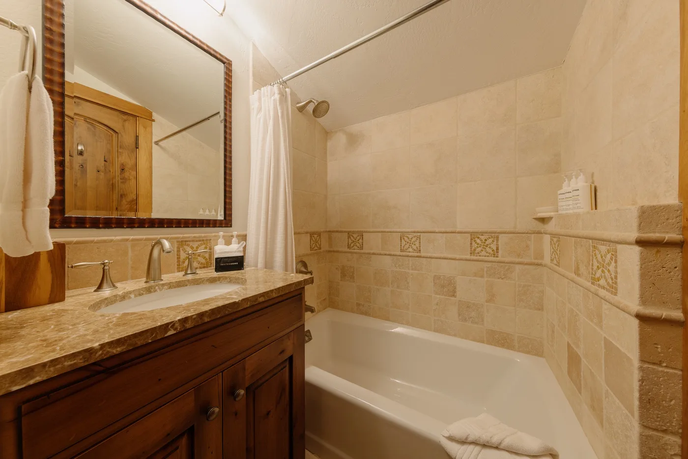A bathroom with a bathtub, shower, and wood vanity.