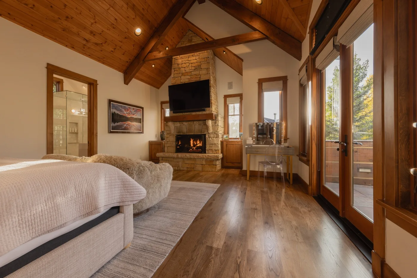 A bedroom with a fireplace, television, and glass doors opening onto a balcony.