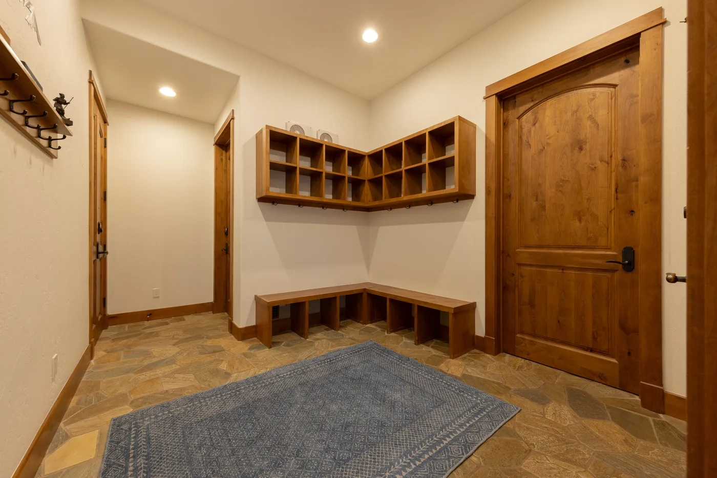 An entryway with wooden cubbies, a bench, and a rug.