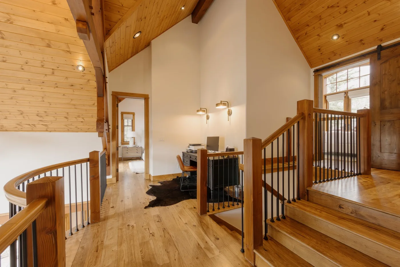 A wood-paneled loft landing with a desk and stair railings.