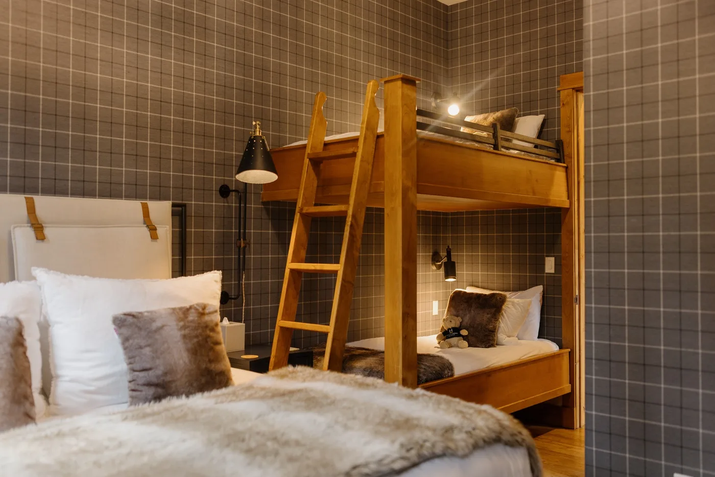 A cozy bedroom with wooden bunk beds and tiled walls.