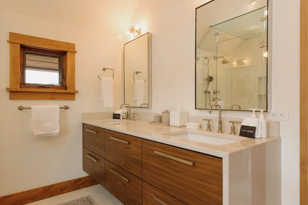 A bathroom vanity with a long countertop, sinks, and a large wall mirror.