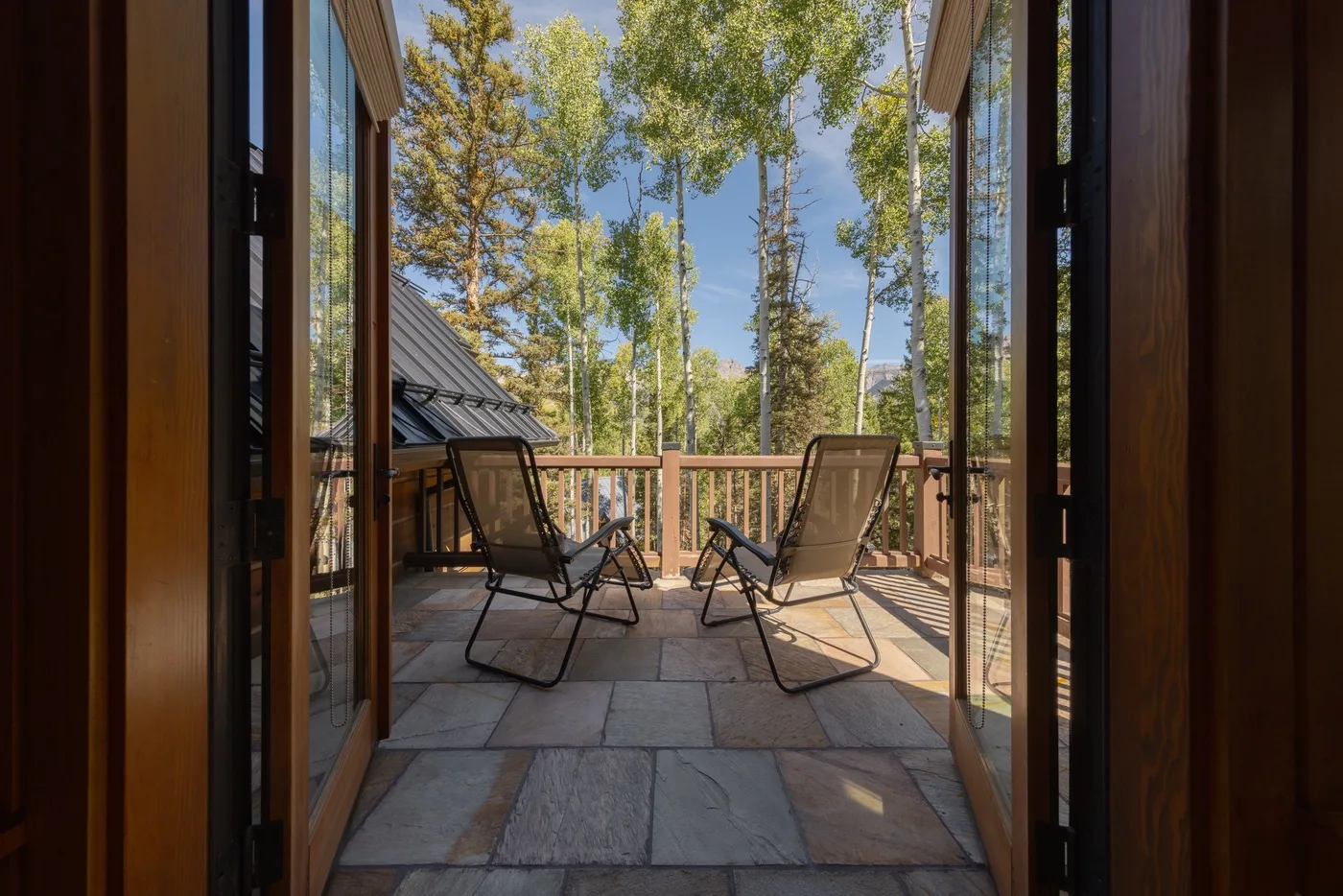 A patio with two reclining seats overlooks a wooded landscape.