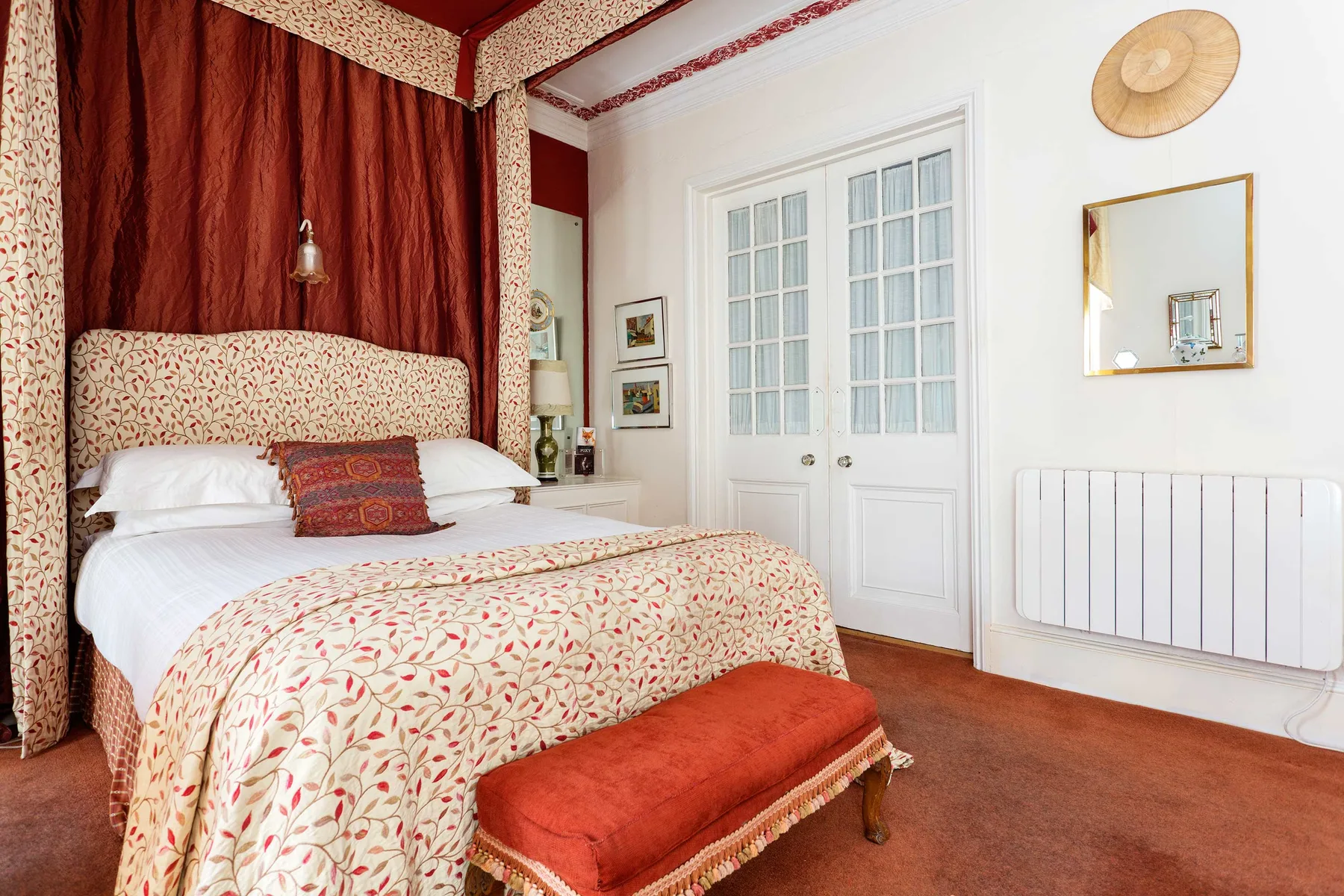 A bedroom with a patterned bedspread and red curtains.
