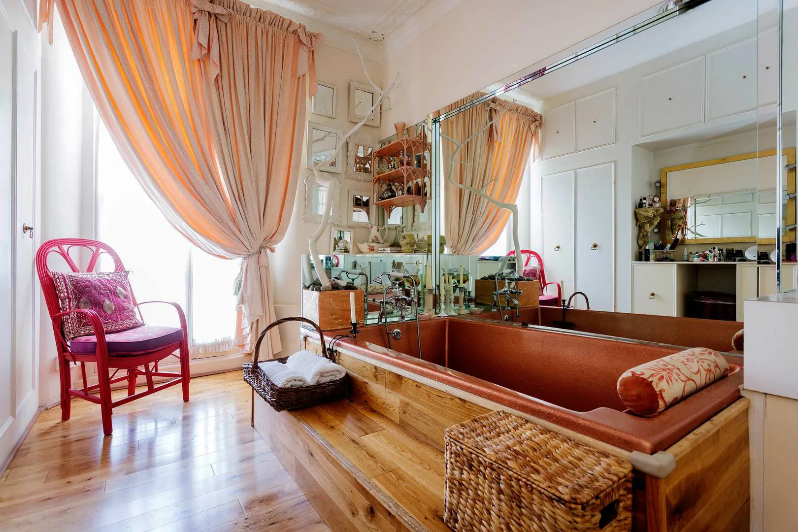 A bright room with a large mirror, a cushioned built-in bench, and wooden flooring.