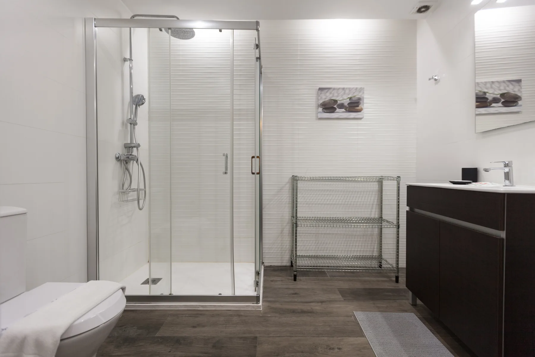A modern bathroom with a glass shower and dark vanity.