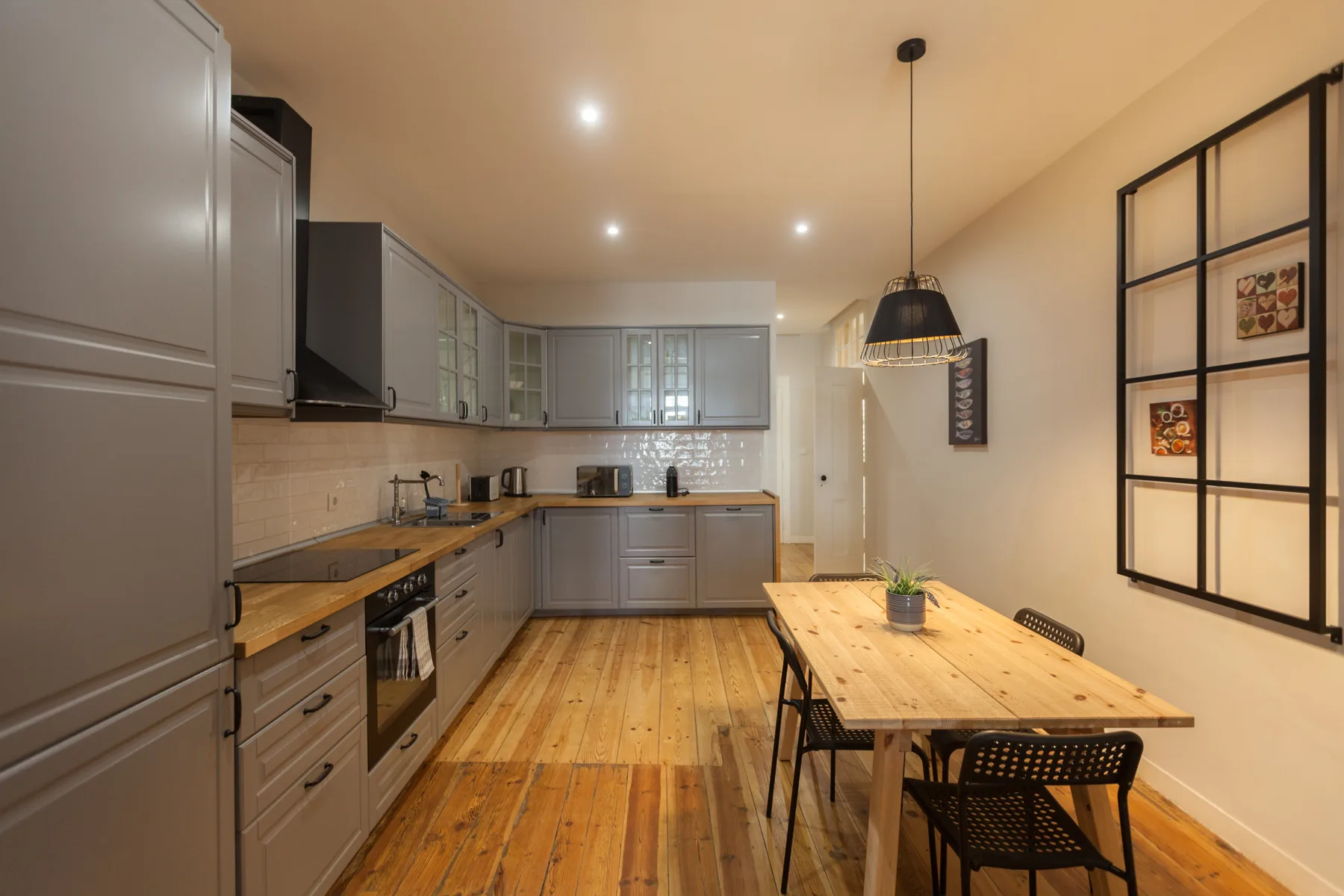 A kitchen and dining area with a long wooden table and gray cabinets.