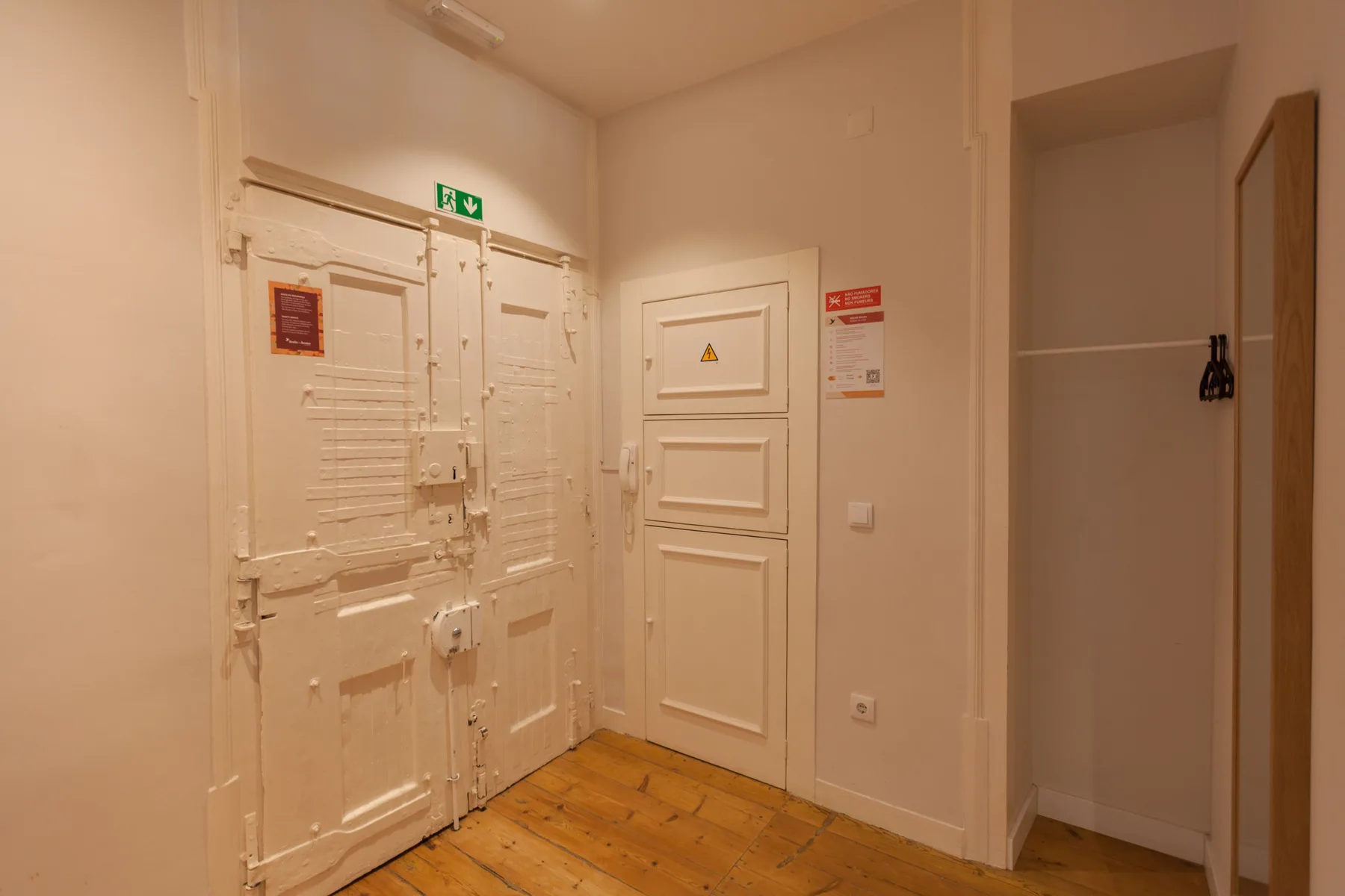 An interior hallway with white doors and a wooden floor.