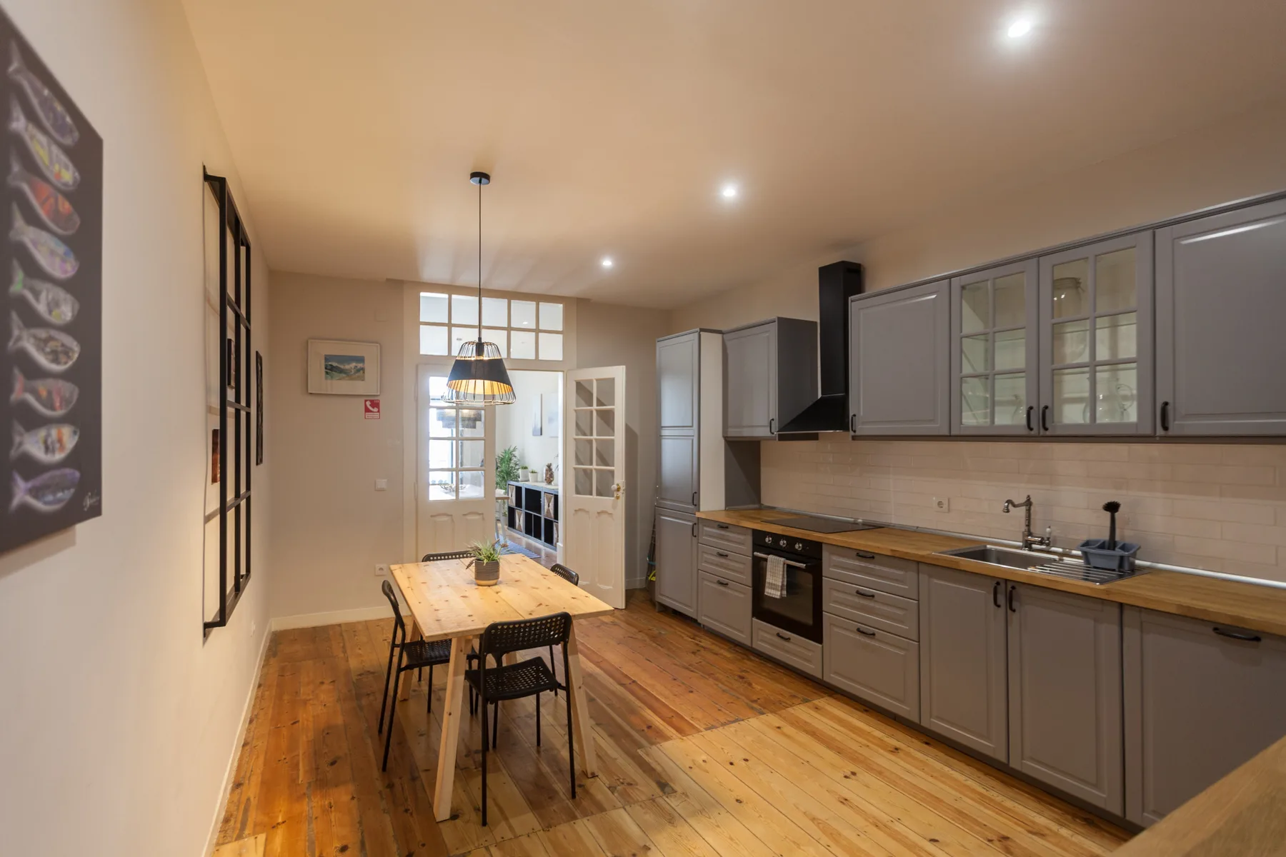 A kitchen and dining area with gray cabinetry and a wooden table.