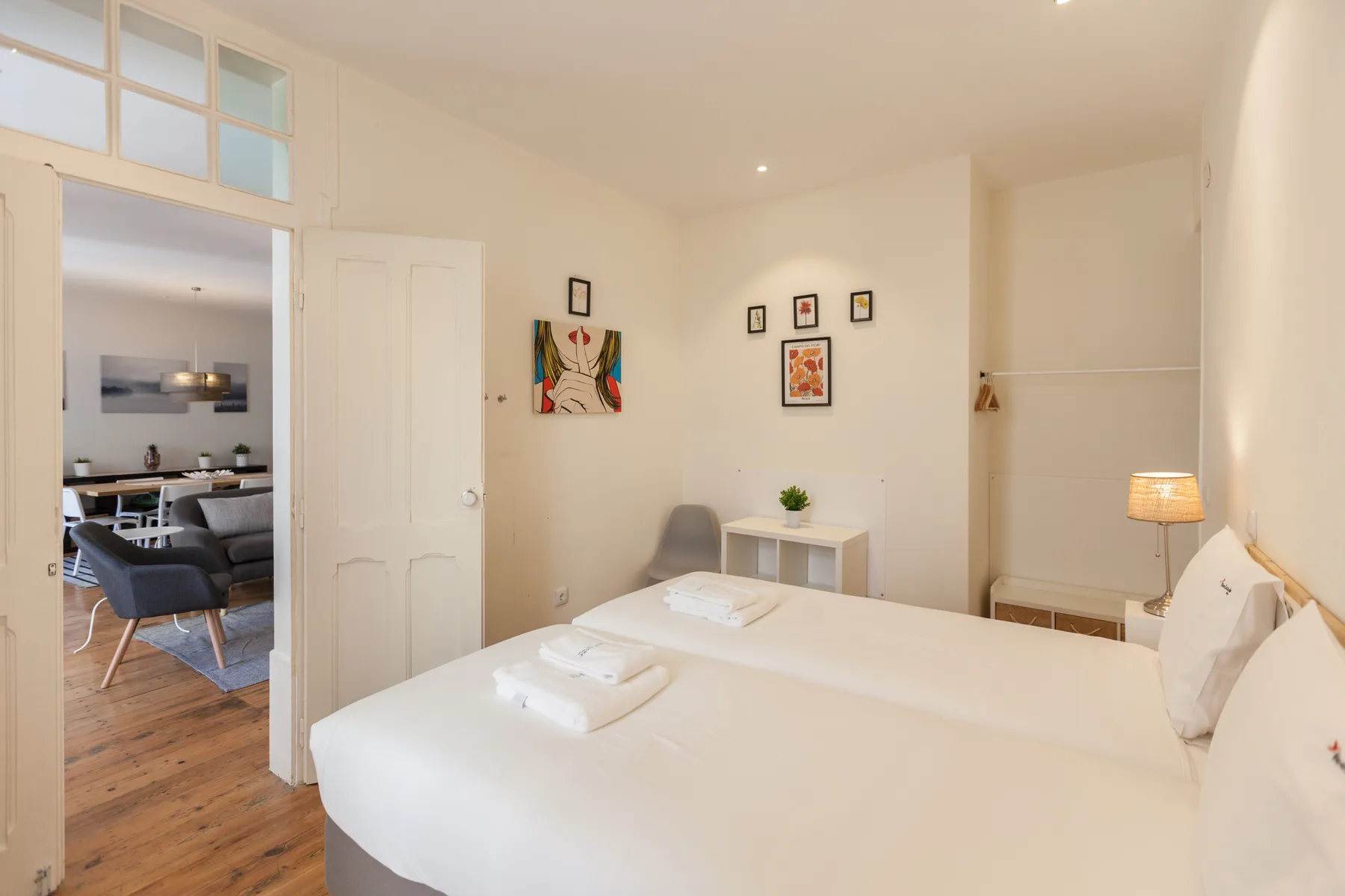 A bright bedroom with a neatly made bed and a small table against the wall.