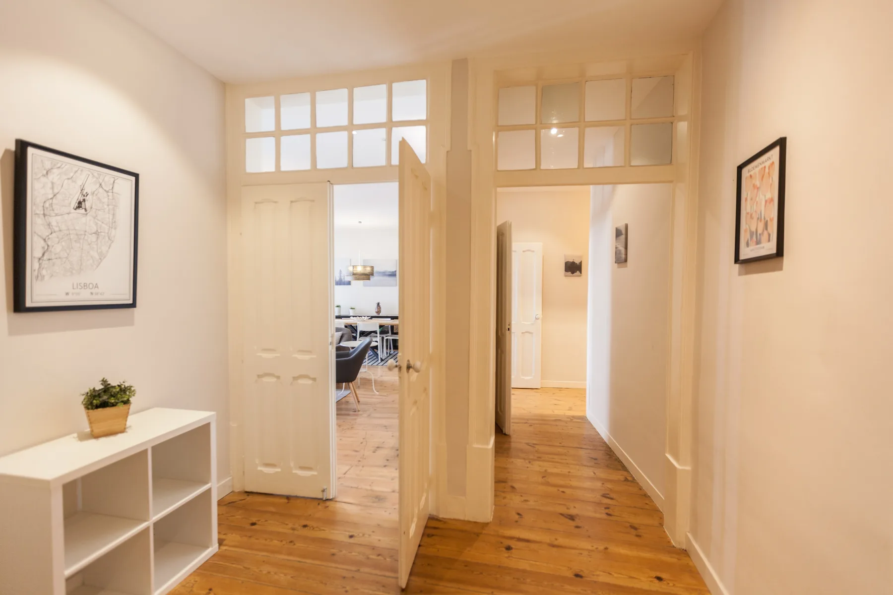 A bright interior hallway with wooden flooring and open doorways.