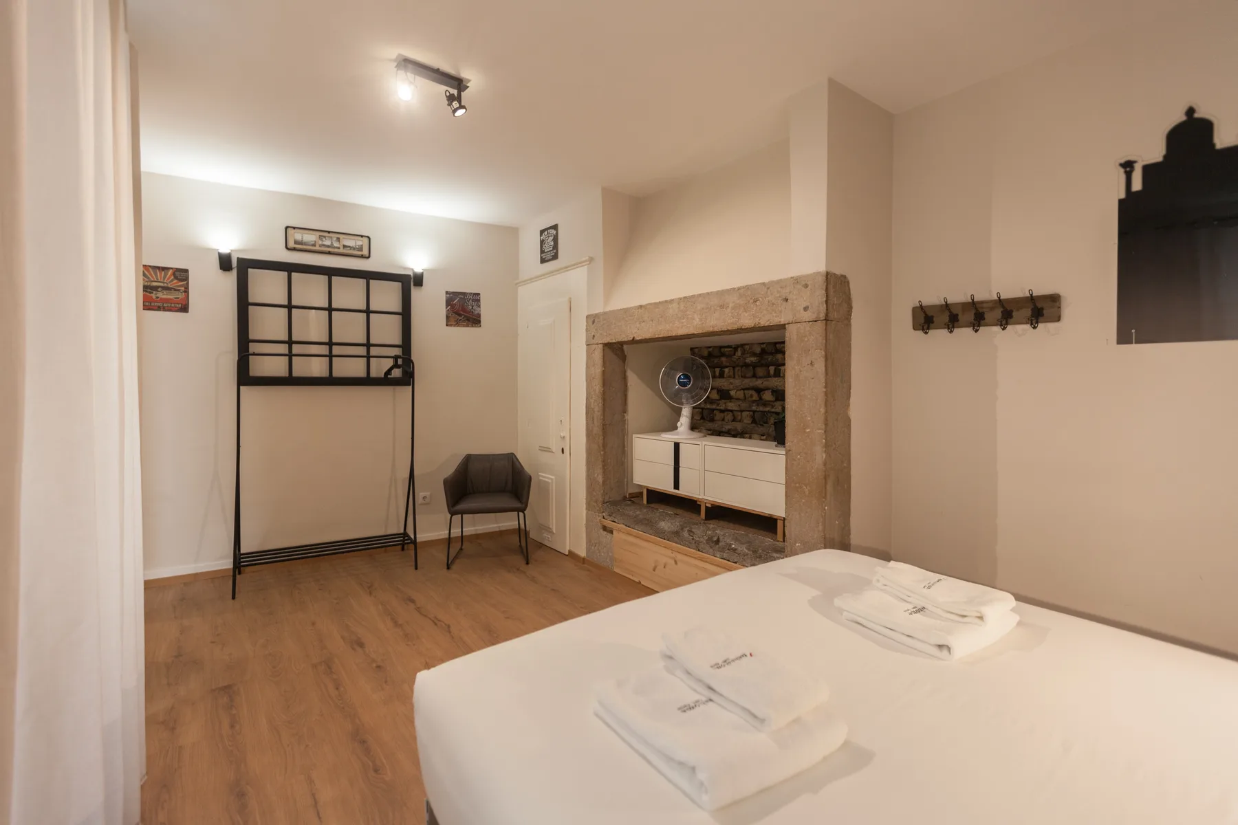 A bedroom with a bed, folded towels, and a small seating area.