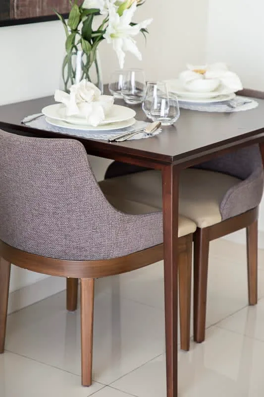 A dining table is set with plates, glasses, and white flowers.