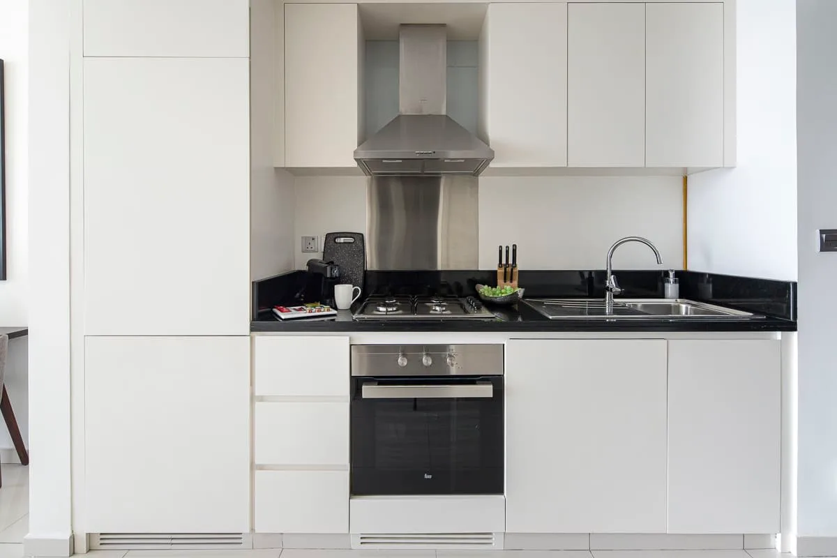 Una cocina moderna con gabinetes blancos, una estufa y un fregadero.