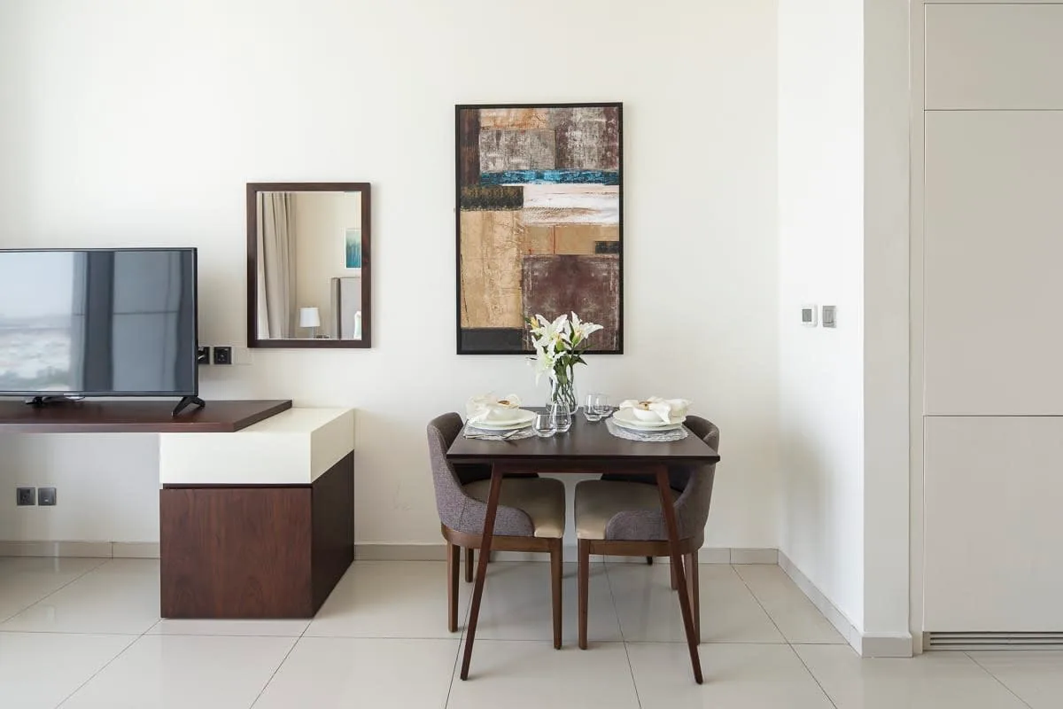A dining area with a table and chairs beside a television stand.