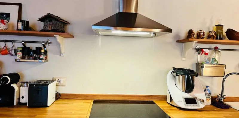 A kitchen counter with appliances beneath a stainless steel range hood.