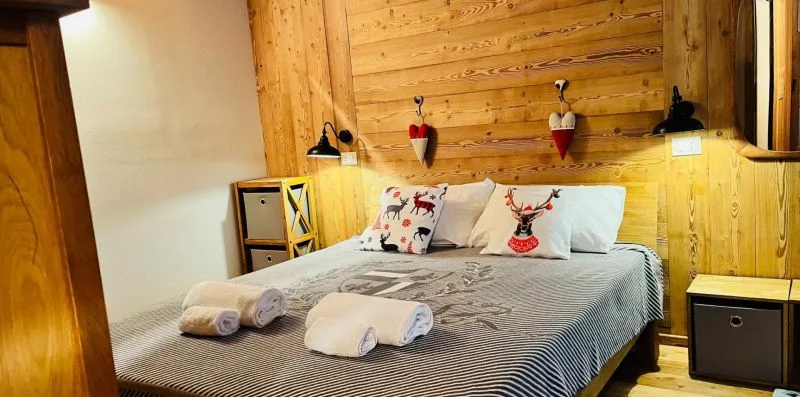 A bedroom with a bed dressed in gray bedding against wood-paneled walls.
