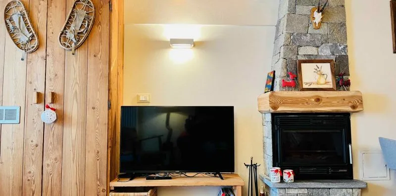 A living room with a television and a stone fireplace.
