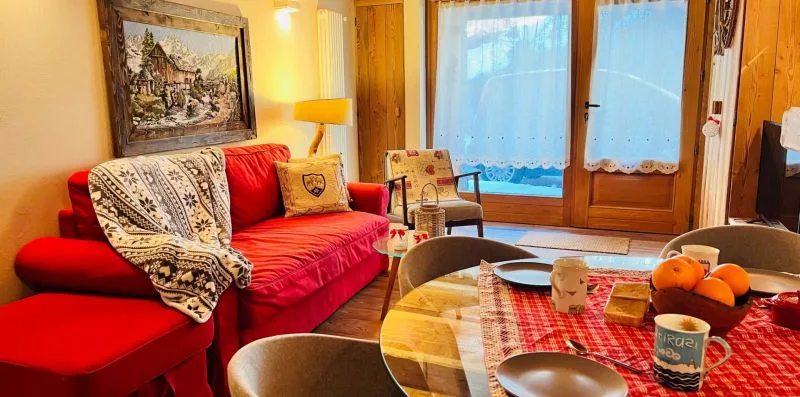 A living room with red seating beside a round table and glass doors.