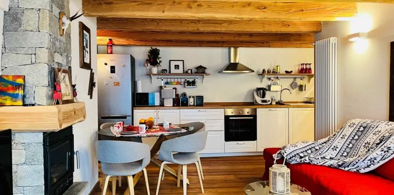 A rustic living and kitchen area with a dining table and wood ceiling beams.
