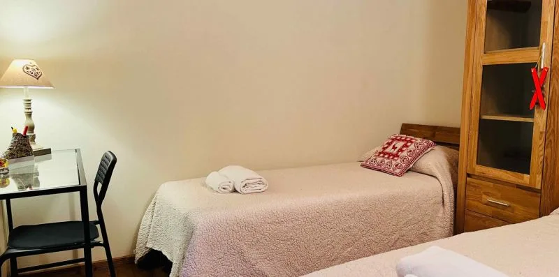 A bedroom with a single bed, folded towels, and a small desk.