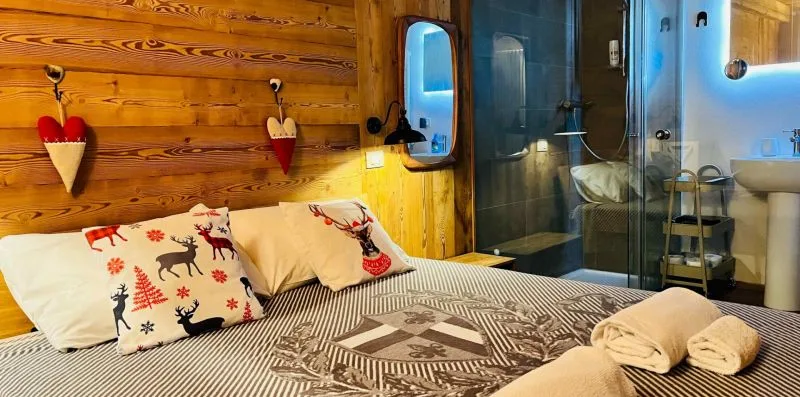 A bedroom with patterned bedding and a glass-enclosed shower area.
