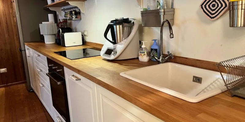 A kitchen counter with a sink, cooktop, and small appliances.