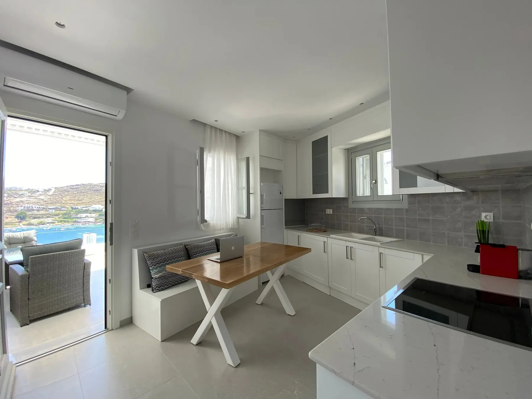 A bright kitchen and dining area with a table beside the open patio doorway.