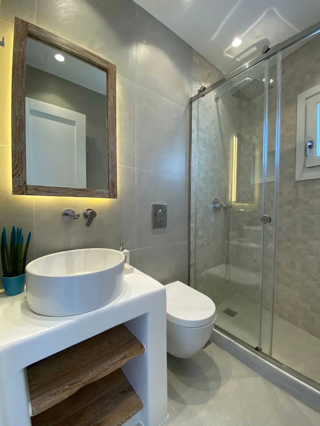 A modern bathroom with a vessel sink and glass shower.