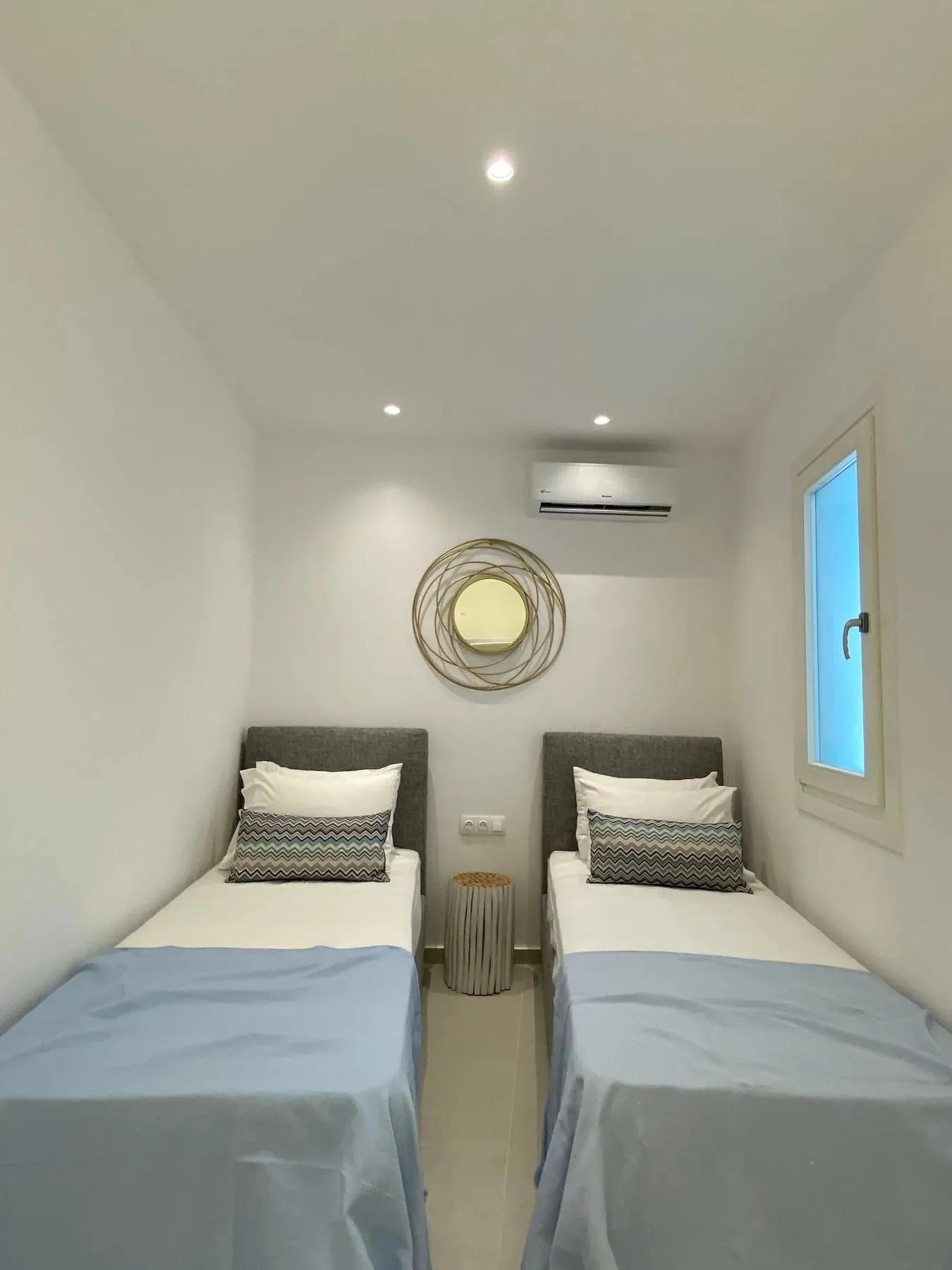 A twin bedroom with two single beds and a circular wall decoration.