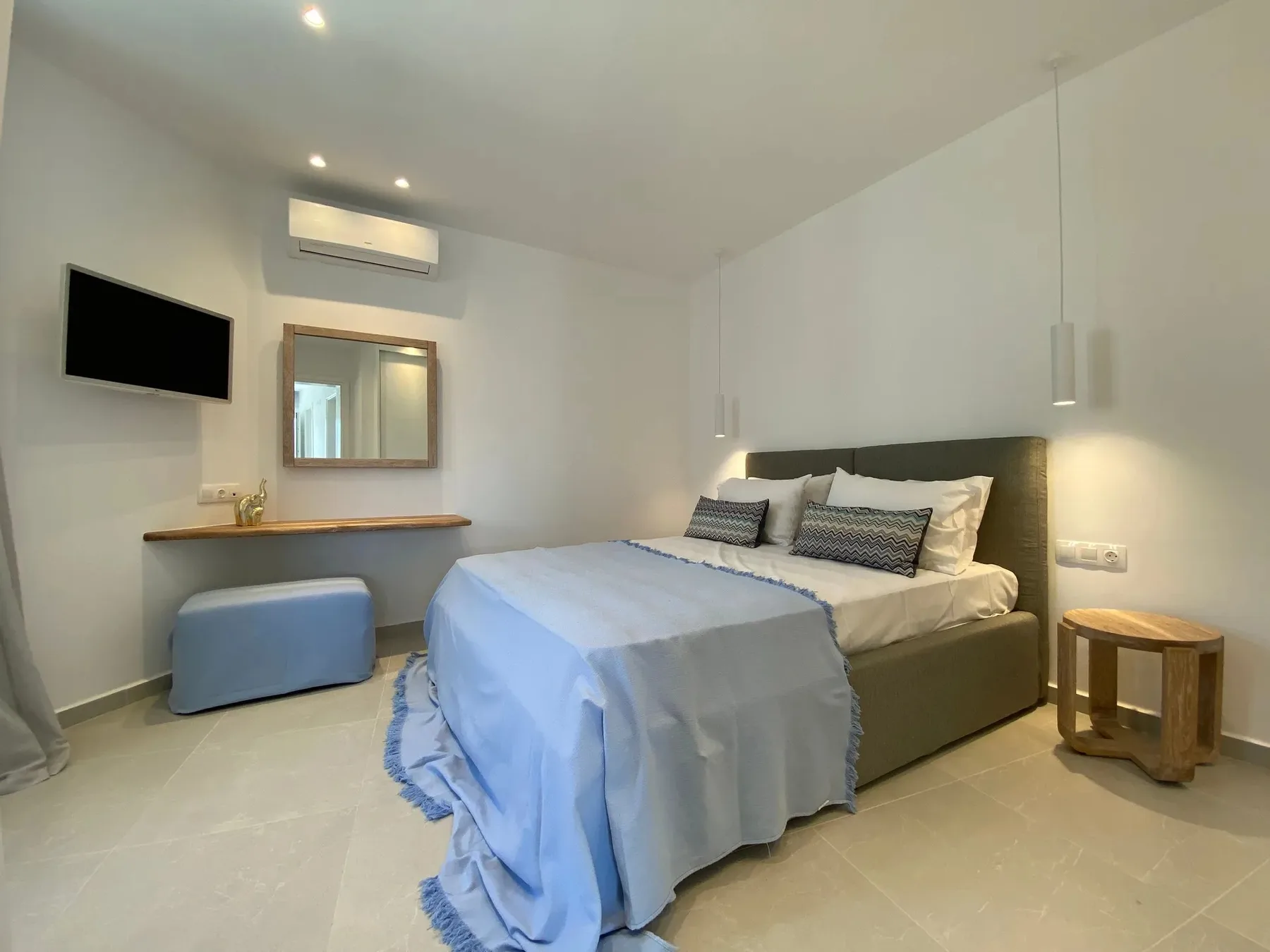 A bedroom with a neatly made bed and a desk along the wall.