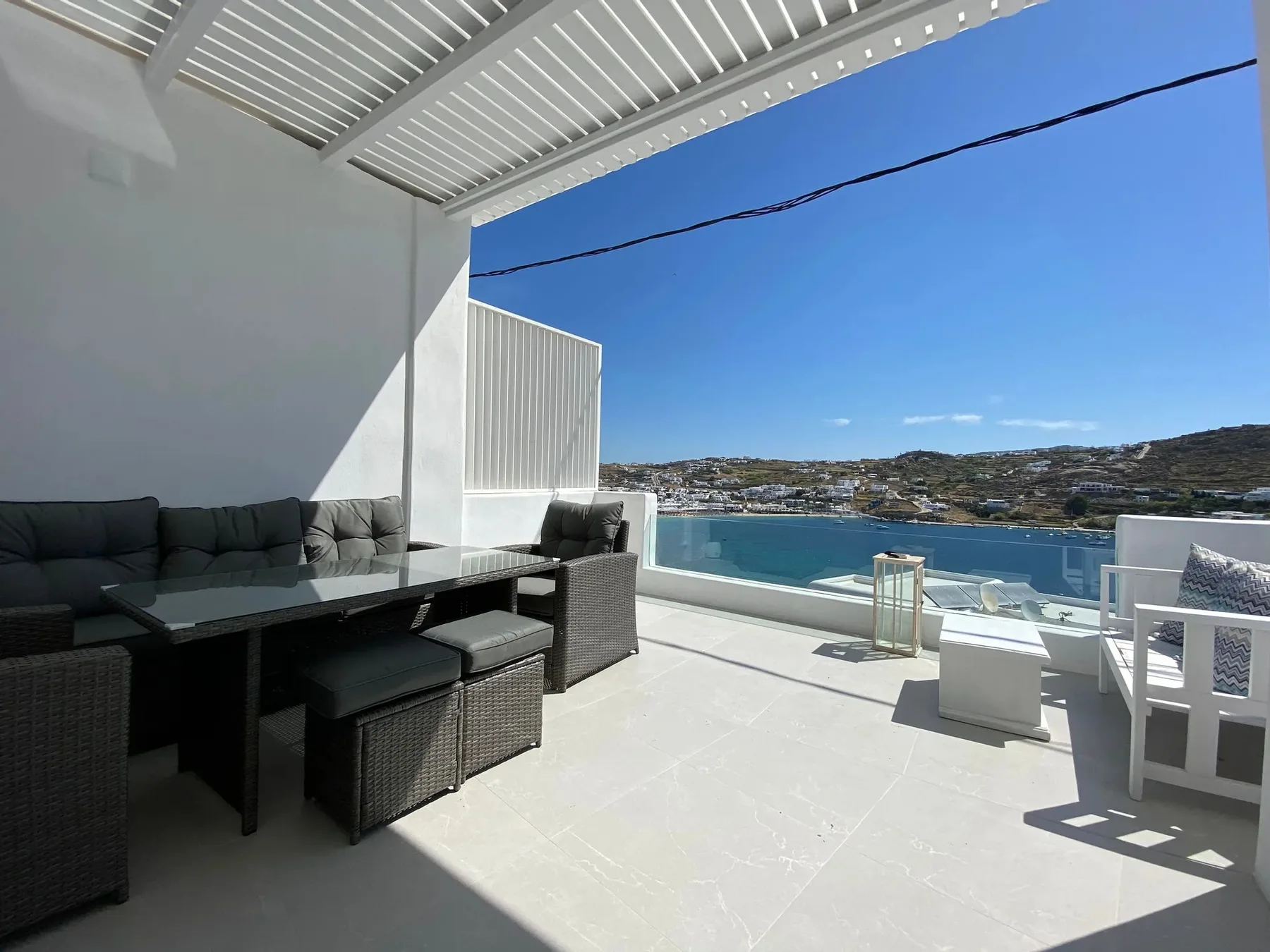A sunny outdoor terrace with seating overlooking the water.