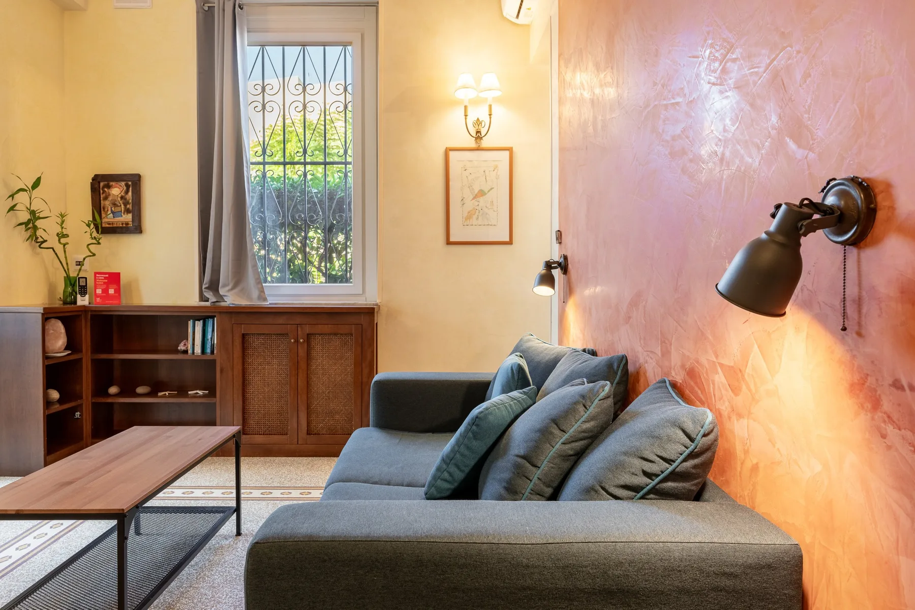 A living room with blue seating beside a textured pink wall.