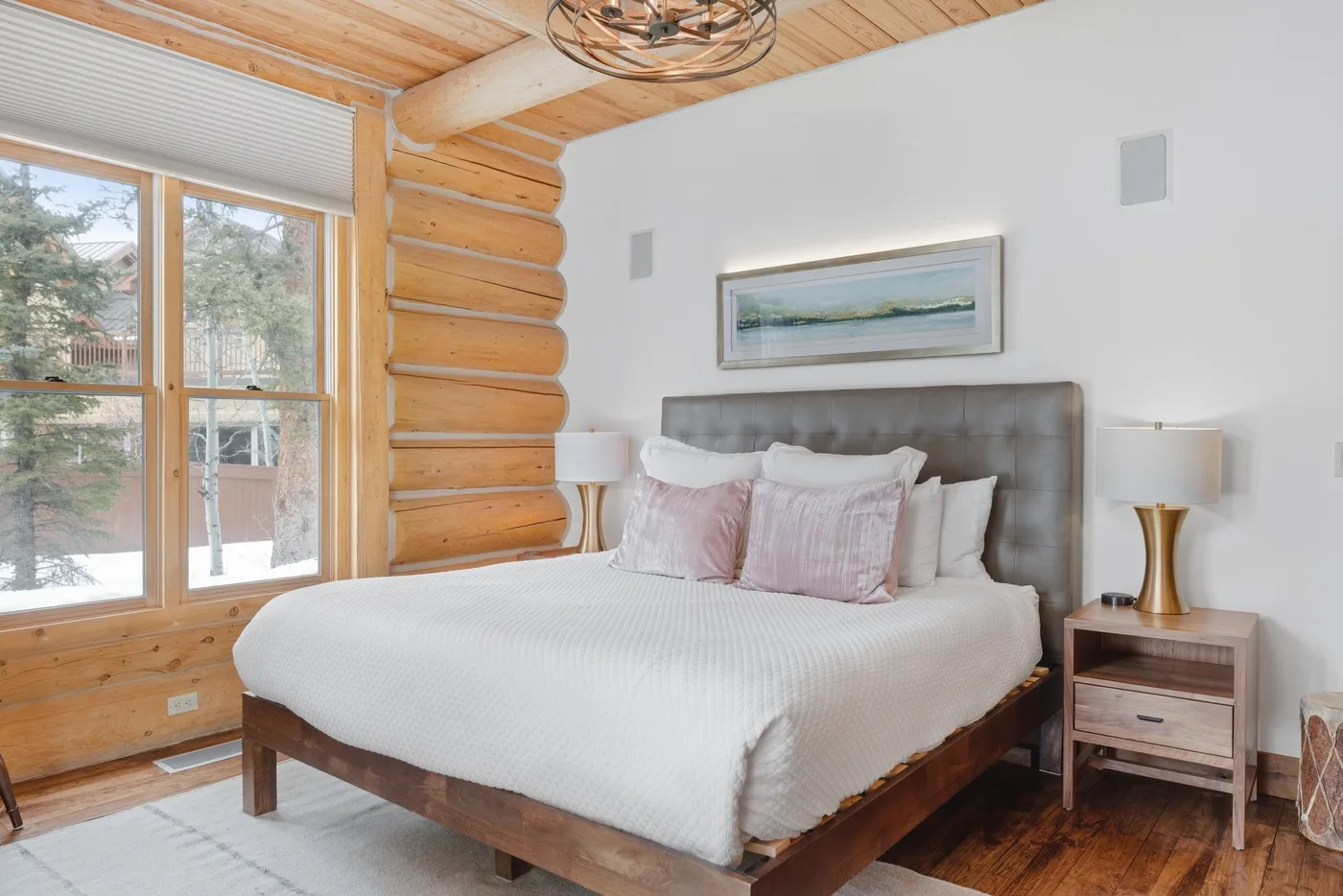 A bedroom with a large bed, wood-paneled walls, and wide windows.
