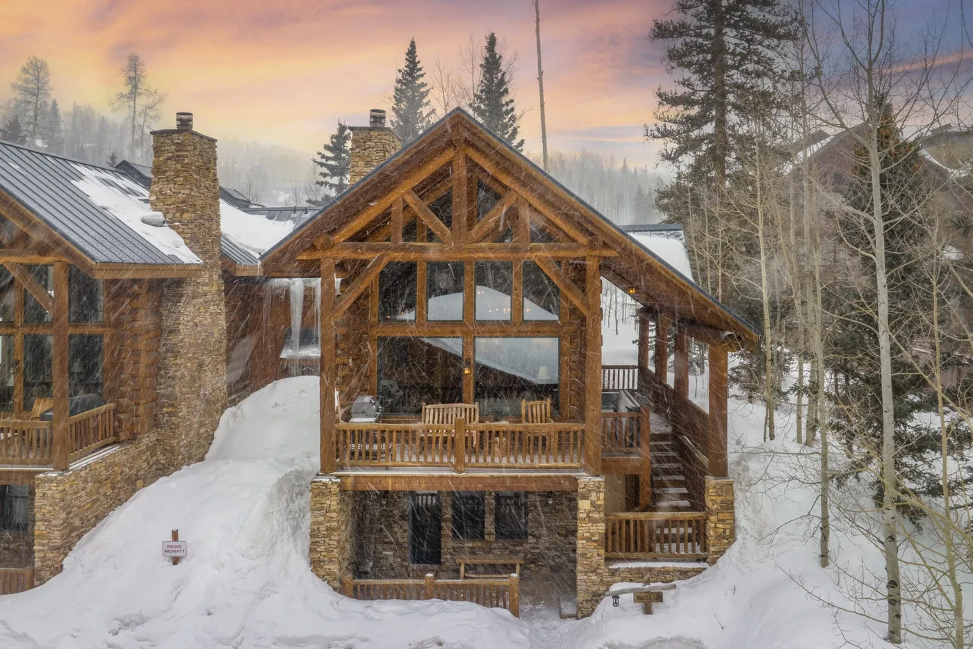 A timber-and-stone lodge stands amid deep snow and evergreen trees.