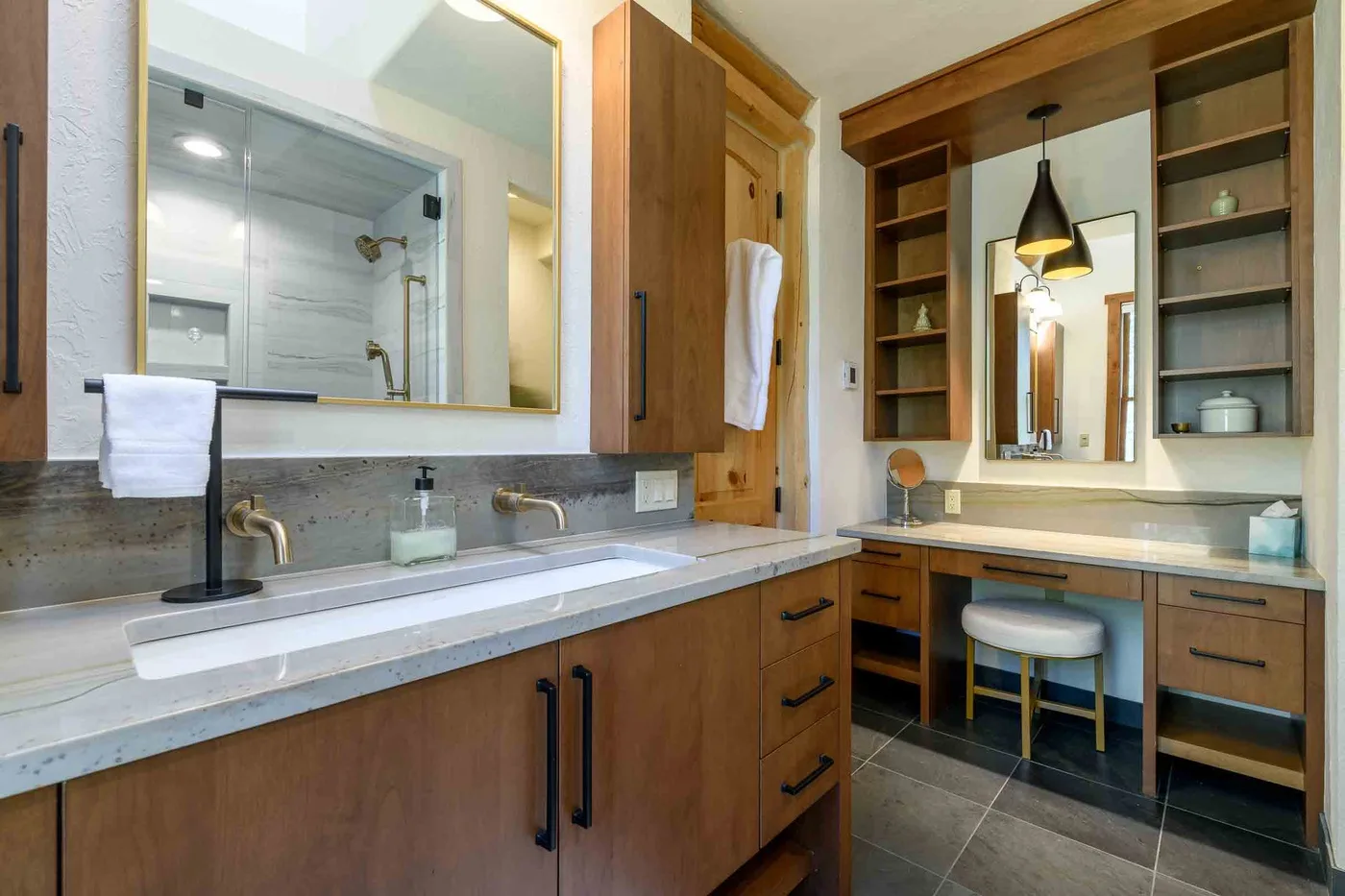 A bathroom vanity with a large mirror and a separate sink area.