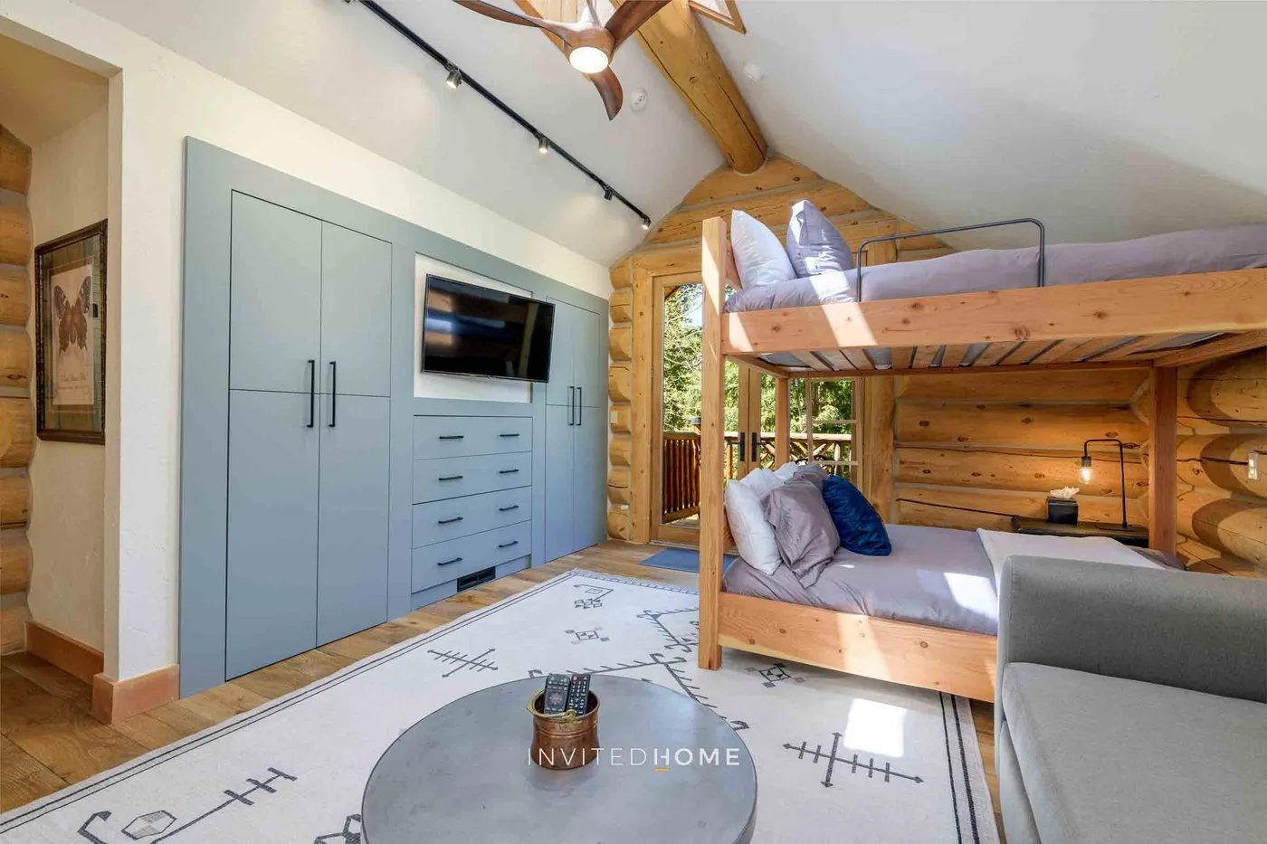 A wood-paneled bedroom with a bunk bed, built-in cabinets, and a television.
