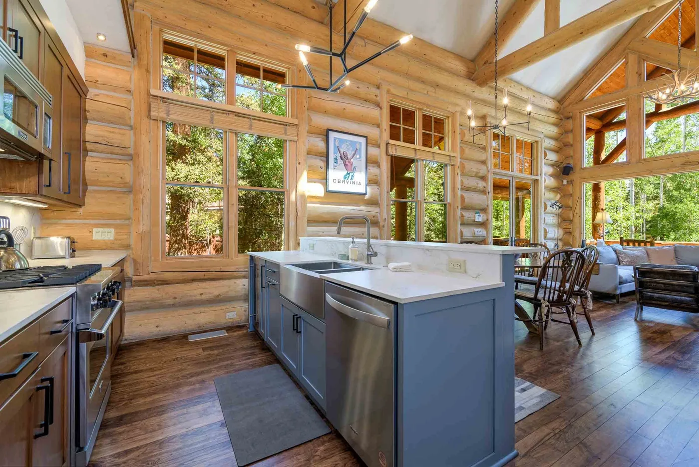 A timber cabin kitchen opens into a bright dining and seating area.